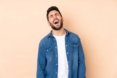 Beyaz tenli yakışıklı adam bej arka planda izole edilmiş gülüyor.