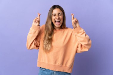 İzole edilmiş mor arka planı olan genç İspanyol kadın, şans diliyor.