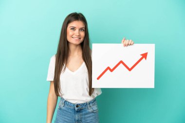 Mavi arka planda izole edilmiş genç beyaz bir kadın elinde büyüyen bir istatistik okuyla mutlu bir ifade ile bir işaret tutuyor.