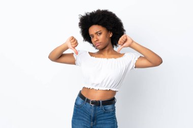 Beyaz arka planda izole edilmiş genç Afrikalı Amerikalı kadın baş parmağını iki eliyle aşağı gösteriyor.