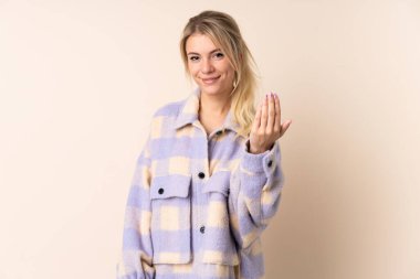 Sarışın kadın soyutlanmış arka planda. Eli ile gelmesi için davet ediyor. Gelmene sevindim.