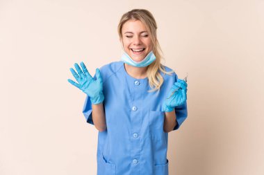 Dişçi kadın arka planda aletlerle gülüyor.