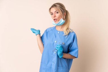 İzole edilmiş arka plan üzerinde araçları tutan dişçi kadın, el bilgisayarı üzerinde görsel alan tutuyor.