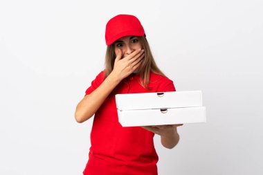 Pizza teslimatı yapan kadın elinde pizza tutuyordu. Koronavirüsten koruyordu. Yüzünde şaşkınlık ve şok ifadesi olan beyaz bir duvarın üzerindeydi.