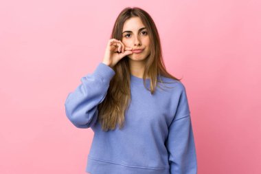 Soyutlanmış pembe arka planda genç bir kadın sessizlik işareti gösteriyor.