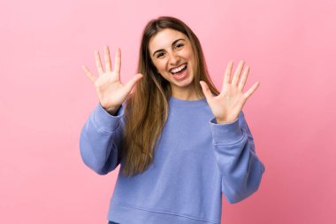 Soyutlanmış pembe arka planı olan genç bir kadın parmaklarıyla ona kadar sayıyor.