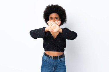 Beyaz arka planda izole edilmiş genç Afrikalı Amerikalı bir kadın bir eylemi durdurmak için elleriyle dur hareketi yapıyor.