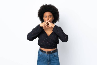 Beyaz arka planda izole edilmiş genç Afrikalı Amerikalı kadın sessizlik işareti gösteriyor.