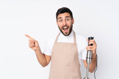 Beyaz arka planda izole edilmiş el blenderi kullanan adam şaşırdı ve parmağını yana çevirdi.