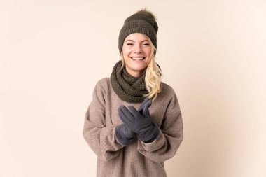 Kışlık şapkalı genç bir kadın izole bir arka planda alkışlıyor.