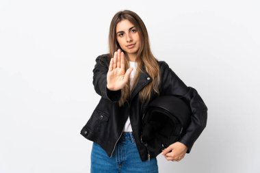 İzole edilmiş beyaz arka planda motosiklet kaskı tutan genç bir kadın eliyle durdurma hareketi yapıyor.