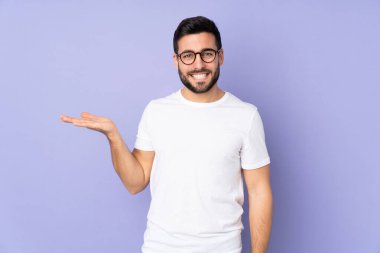 Kafkasyalı yakışıklı, izole edilmiş arka plan üzerinde. Avucunun içinde hayali bir ilan tutuyor.