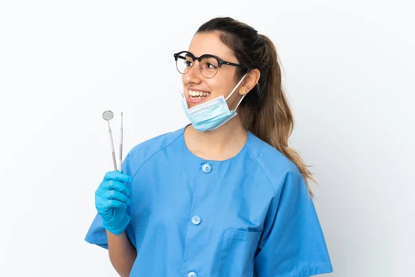 Młoda Kobieta Dentysta Trzyma Narzędzia Izolowane Białym Tle Patrząc Bok — Zdjęcie stockowe