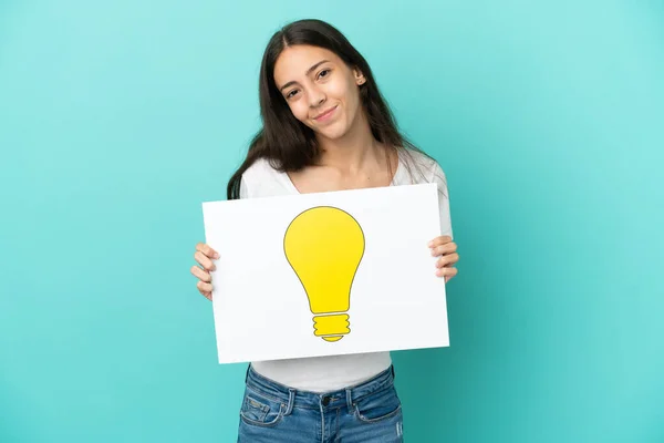 Young French Woman Isolated Blue Background Holding Placard Bulb Icon — Stock Photo, Image