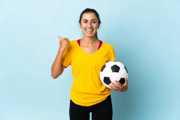 Joven Futbolista Hispana Aislada Sobre Fondo Azul Apuntando Hacia Lado —  Fotos de Stock