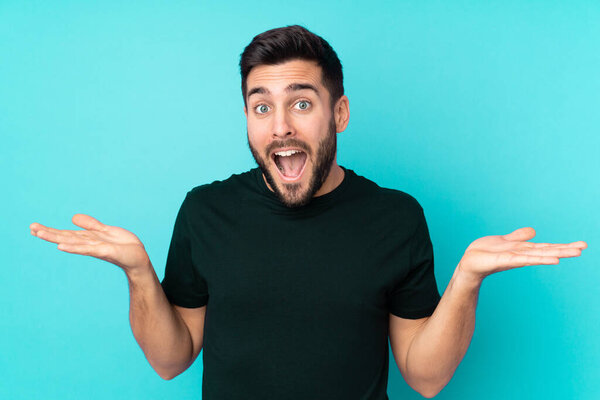 Caucasian handsome man isolated on blue background with shocked facial expression