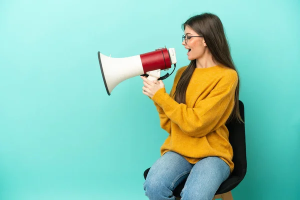 Young Caucasian Woman Sitting Chair Isolated Blue Background Shouting Megaphone — Stock Photo, Image