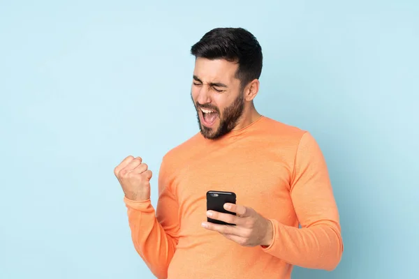 Caucásico Hombre Guapo Con Teléfono Posición Victoria Sobre Fondo Azul —  Fotos de Stock