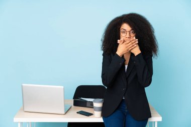 İş yerinde çalışan Afrikalı Amerikalı iş kadını elleriyle ağzını kapatıyor.