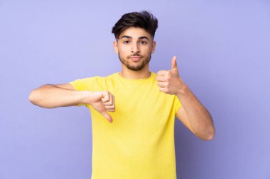 Soyutlanmış geçmişi olan yakışıklı Arap bir adam iyiye-kötüye işaret yapıyor. Evet ya da hayır arasında kararsız