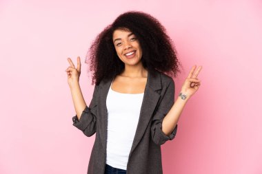 Genç Afro-Amerikan kadın izole edilmiş arka planda iki eliyle zafer işareti gösteriyor.