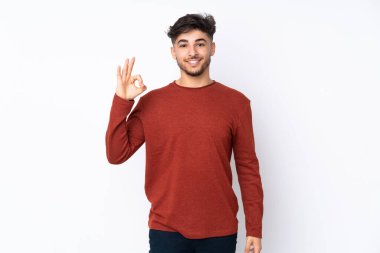 İzole edilmiş arka planda yaşayan Arap yakışıklı adam parmaklarıyla tamam işareti gösteriyor.