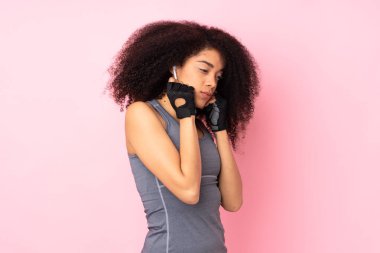 Genç Afrikalı Amerikalı spor kadın pembe arka planda izole edilmiş müzik dinliyor.