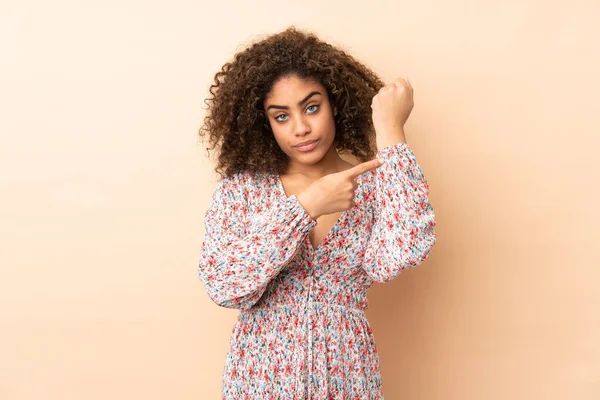 Genç Afrikalı Amerikalı kadın bej arka planda izole edilmiş, geç kalma jesti yapıyor.