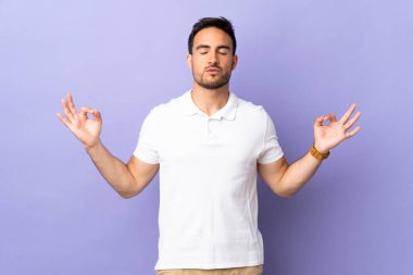 Mor arka planda, Zen pozisyonunda izole genç yakışıklı bir adam.