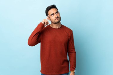 Soyutlanmış arka planda genç yakışıklı bir adam deliliğin hareketini yapıyor. Parmağını kafaya koyuyor.