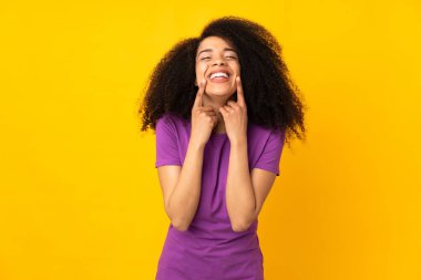 Mutlu ve hoş bir ifadeyle gülümseyen, soyutlanmış bir geçmişi olan genç Afrikalı Amerikalı kadın.