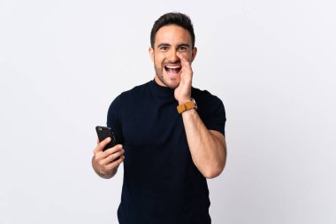 Beyaz arka planda izole edilmiş cep telefonu kullanan beyaz bir adam ağzı açık bağırıyor.