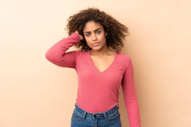 Genç Afrikalı Amerikalı kadın bej arka planda izole edilmiş. Şüpheleri var.