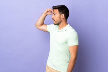 Mor arka planda yalıtılmış genç ve yakışıklı bir adam.