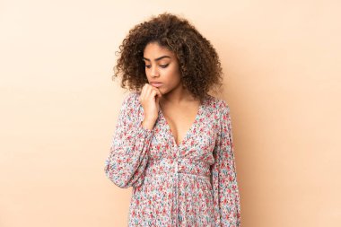 Genç Afrikalı Amerikalı kadın bej arka planda izole edilmiş. Şüpheleri var.