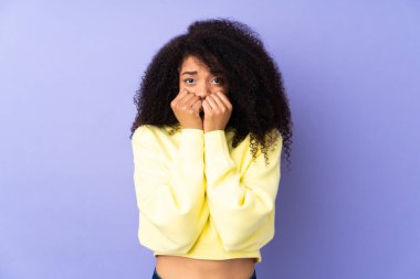 Genç Afrikalı Amerikalı kadın mor arka planda izole edilmiş gergin ve korkmuş bir şekilde elleriyle suni teneffüs yapıyor.