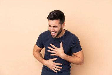 Beyaz tenli yakışıklı adam bej arka planda izole edilmiş, çok gülümsüyor.