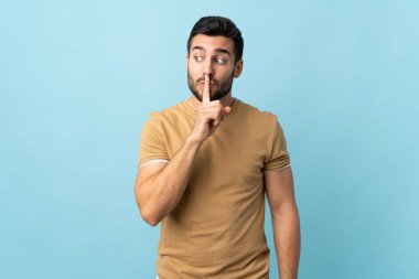 Sakallı ve sakallı genç bir adam sessiz bir jest işareti gösteriyor. Parmağını ağzına sokuyor.