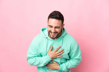 Beyaz tenli yakışıklı bir adam pembe arka planda izole edilmiş, sürekli gülümsüyor.