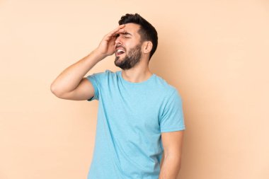 Beyaz tenli yakışıklı adam bej arka planda izole edilmiş, çok gülümsüyor.