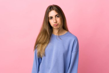 Hüzünlü bir ifadeyle soyutlanmış pembe arka planı olan genç bir kadın