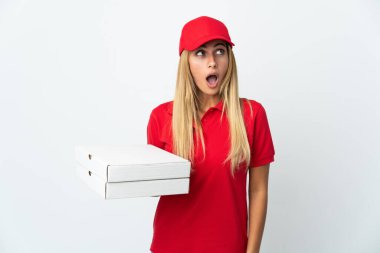 Pizzacı kadın beyaz arka planda izole edilmiş bir pizza tutuyor ve şaşırmış bir şekilde yukarı bakıyor.