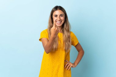 Soyutlanmış mavi arka planda genç bir İspanyol kadın geliyor.