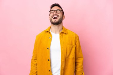Beyaz tenli yakışıklı adam pembe arka planda izole edilmiş gülüyor.