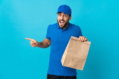 Mavi arka planda sakallı teslimatçı şaşırdı ve parmağını yana çevirdi.