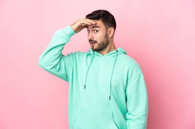 Young caucasian handsome man isolated on pink background doing surprise gesture while looking front