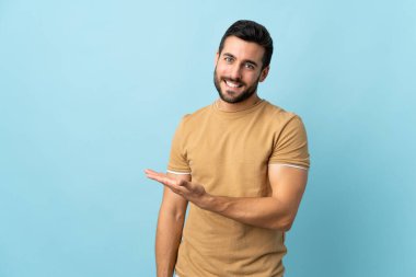 Arka planda sakallı yakışıklı genç bir adam bir fikir sunarken gülümsüyor.