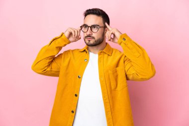 Pembe arka planda soyutlanmış beyaz, yakışıklı genç bir adam. Şüpheleri ve düşünceleri var.