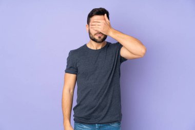 Beyaz tenli yakışıklı adam elleriyle gözlerini kapatıyor. İzole edilmiş mor arkaplan üzerinde bir şey görmek istemiyorum