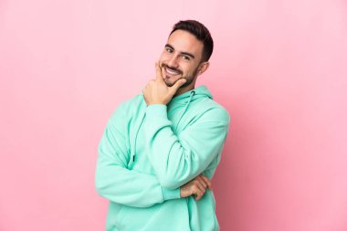 Beyaz tenli yakışıklı bir adam pembe arka planda izole edilmiş mutlu ve gülümsüyor.